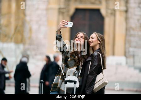 Zwei weibliche Touristen, die gerne europäische Städte erkunden, Konzept von Tourismus und Reisen, Frauen mit Koffern, die durch die Stadt laufen, modern Stockfoto