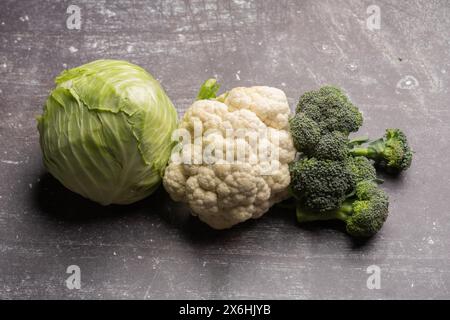 Frischer Brokkoli, Blumenkohl und Kohl, frisch geerntet, ökologisch angebaut, auf einem grauen rustikalen Hintergrund Stockfoto