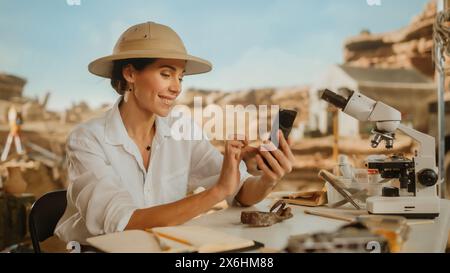 Archäologische Ausgrabungsstätte: Berühmte Archäologin forscht mit dem Smartphone die Entdeckung fossiler Überreste und Artefakte der Kultur der Antike in sozialen Medien im Internet Stockfoto