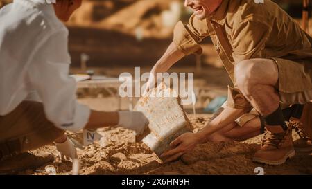 Archäologische Ausgrabungsstätte: Zwei große Archäologen arbeiten an der Ausgrabungsstätte, sorgfältig säubern, neu entdeckte kulturelle Artefakte der antiken Zivilisation, historische Tontafel, fossile Überreste Stockfoto