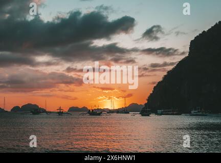 Boote ankern in einer ruhigen Bucht bei Sonnenuntergang in der Nähe von malerischen Inseln. Philippinen, Palawan. Stockfoto