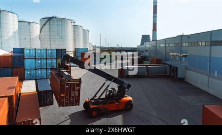 Luftaufnahme eines Container Handlers mit einem großen roten Frachtcontainer in einem Werftterminal. Der Fahrer der Maschine lädt die Kiste im Logistikzentrum. Stockfoto