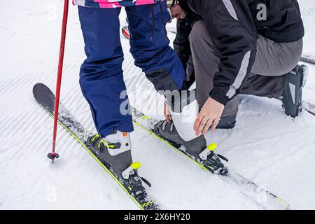 Dad hilft seiner Tochter, ihren Schuh am Schuh zu befestigen. Aktiver Familienurlaub Stockfoto