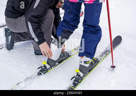 Dad hilft seiner Tochter, ihren Schuh am Schuh zu befestigen. Aktiver Familienurlaub Stockfoto