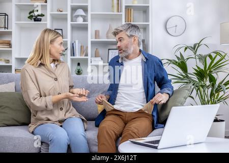 Ein Paar mittleren Alters hatte ein ernsthaftes Gespräch über finanzielle Probleme und saß auf einem gemütlichen Sofa in ihrem Wohnzimmer. Stockfoto