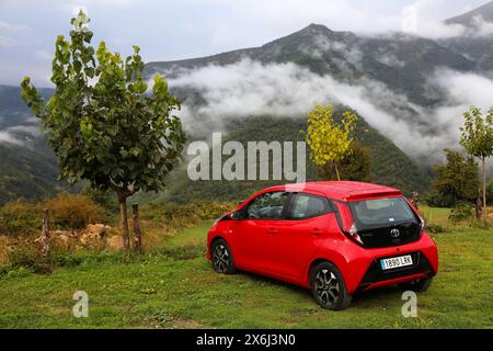 HUESCA, SPANIEN - 25. SEPTEMBER 2021: Toyota Aygo kleines rotes Fließheck-Auto parkt abseits der Straße auf Gras in den Pyrenäen in Spanien. Stockfoto