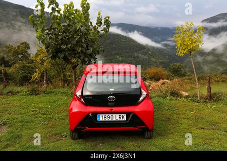 HUESCA, SPANIEN - 25. SEPTEMBER 2021: Toyota Aygo kleines rotes Fließheck-Auto parkt abseits der Straße auf Gras in den Pyrenäen in Spanien. Stockfoto