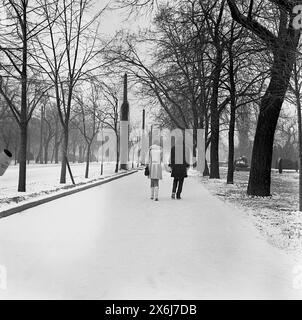 Rumänien, ca. 1973. Ein junges Paar, das während des Winterschnees auf einer Straße der Stadt läuft und Hände hält. Stockfoto