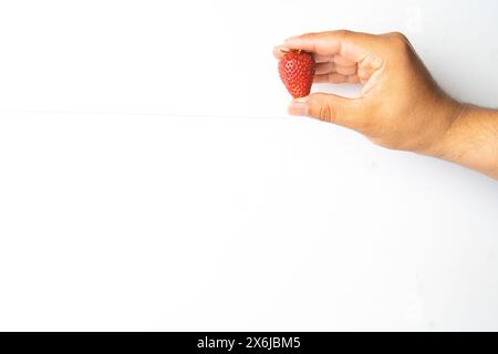 Die Hand des Mannes hält frische Bio-Erdbeeren auf weißem Hintergrund Stockfoto