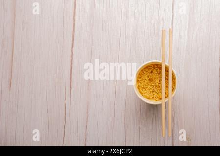 Übersicht über eine Schüssel mit Instant-Pasta-Suppe mit einem Paar Chopstickson auf hellgrauem Hintergrund. Mittagessen. Fastfood-Konzept Stockfoto