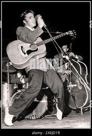 Elvis Presley 1950s Florida Bühnenauftritt mit seiner Gitarre, hielt das Mikrofon, während er in voller Strömung kreiste und spielte Rock & Roll auf der Bühne, mit seiner Gitarre zu Beginn seiner Karriere 1956 Florida USA Stockfoto