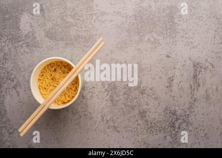 Übersicht über eine Schüssel mit Instant-Pasta-Suppe mit einem Paar Chopstickson auf hellgrauem Hintergrund. Mittagessen. Fastfood-Konzept Stockfoto