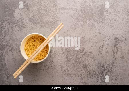 Übersicht über eine Schüssel mit Instant-Pasta-Suppe mit einem Paar Chopstickson auf hellgrauem Hintergrund. Mittagessen. Fastfood-Konzept Stockfoto