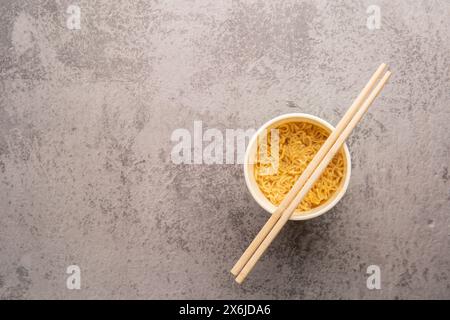 Übersicht über eine Schüssel mit Instant-Pasta-Suppe mit einem Paar Chopstickson auf hellgrauem Hintergrund. Mittagessen. Fastfood-Konzept Stockfoto