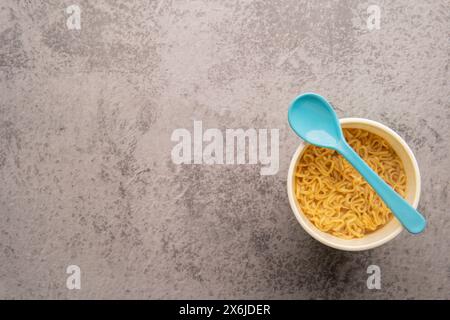 Übersicht über eine Schüssel mit Instant-Pasta-Suppe mit einem Löffel auf hellgrauem Hintergrund. Mittagessen. Fastfood-Konzept Stockfoto