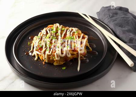 Okonomiyaki-Omelette nach japanischer Art, garniert mit Okonomi-Sauce, japanischer Mayonnaise und Frühlingszwiebeln Stockfoto