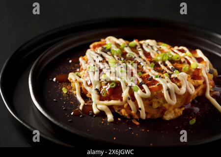 Okonomiyaki Omelette nach japanischer Art, garniert mit Okonomi-Sauce, japanischer Mayonnaise und Frühlingszwiebeln Stockfoto