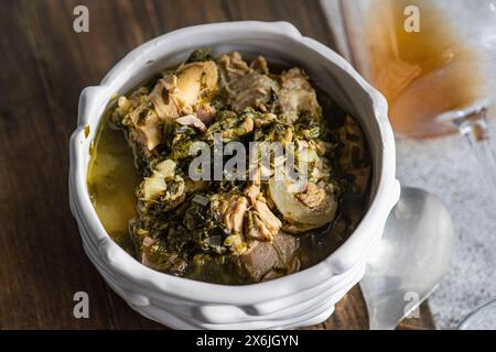 Traditionelles georgianisches Gericht Chakapuli in einer Schüssel und ein Glas Bernsteinwein Stockfoto