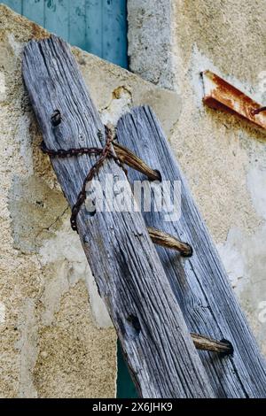 Alte Holzleiter, die an die Wand des Hauses gelehnt ist Stockfoto