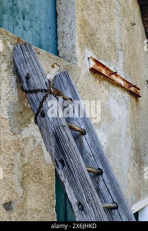 Alte Holzleiter, die an die Wand des Hauses gelehnt ist Stockfoto