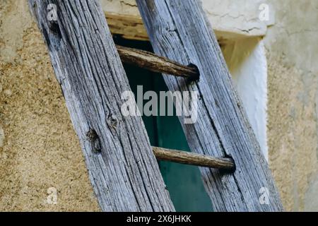 Alte Holzleiter, die an die Wand des Hauses gelehnt ist Stockfoto