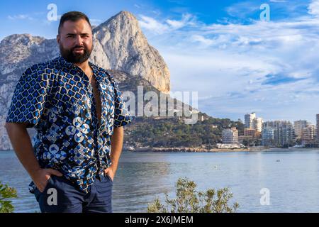 Dieses Porträt zeigt einen 30-jährigen Mann in Calpe, Spanien, während er in der Betrachtung vor dem herrlichen Ifach-Felsen steht. Stockfoto