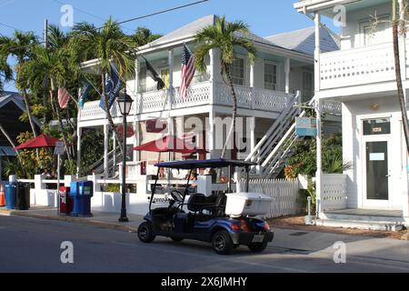 Key West, Florida, USA - 12. Februar 2020: Golfwagen parkt vor wunderschönen weißen Residenzen und Speakeasy Inn and Rum Bar und Palmen in Duv Stockfoto