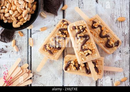 Erdnussbutter-Eis mit Schokoladengriß. Oben sehen Sie die Tischszene über einem weißen Holzhintergrund. Stockfoto