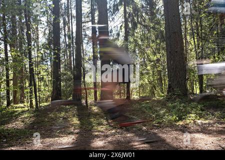 Verschwommenes Bild eines Mannes auf dem Mountainbike auf der Forststraße während des MTB-Radmarathons in Sigulda, Gauja-Nationalpark, Lettland am 12. Mai 2024 Stockfoto