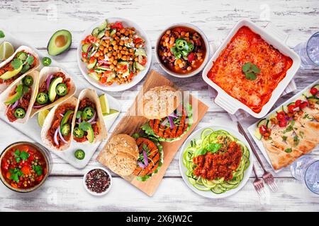 Gesunde pflanzenbasierte vegetarische Mahlzeit-Tischszene. Draufsicht auf weißem Holzhintergrund. Jackfrucht-Tacos, Zucchini-Lasagne, Walnussbolognese-Zoodles, Chi Stockfoto