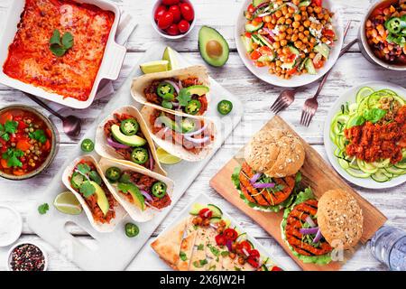 Gesunde pflanzenbasierte vegetarische Mahlzeit-Tischszene. Blick über dem Zimmer auf weißem Holzhintergrund. Jackfrucht-Tacos, Zucchini-Lasagne, Walnussbolognese-Zoodles, c Stockfoto