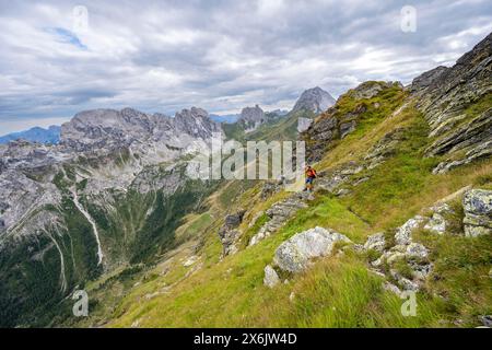 Bergsteiger auf einem schmalen Wanderweg an einem steilen Wiesenhang, Abfahrt von der Raudenspitze, Blick ins Fleonstal mit Felsenberg Stockfoto