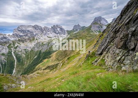 Bergsteiger auf einem schmalen Wanderweg an einem steilen Wiesenhang, Abfahrt von der Raudenspitze, Blick ins Fleonstal mit Felsenberg Stockfoto