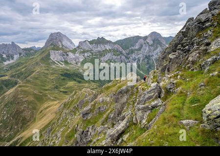 Bergsteiger auf einem schmalen Wanderweg an einem steilen Wiesenhang, Abfahrt von der Raudenspitze, Blick ins Fleonstal mit Felsenberg Stockfoto