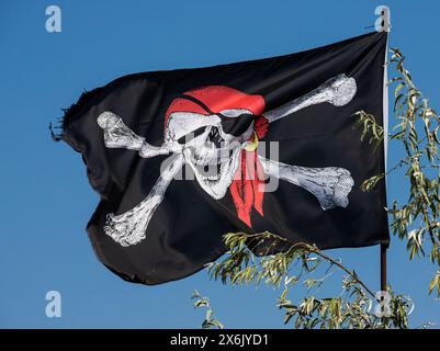 Ein Schädel mit Kreuz, Piratenflagge, die im Wind winkt. Stockfoto