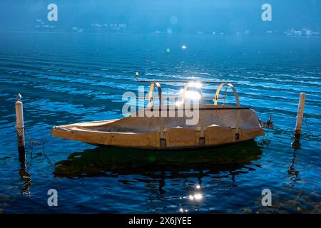 Wunderschönes altes Fischerboot auf dem Luganer See mit Sonnenspiegelung an einem sonnigen Tag in Morcote, Tessin, Schweiz Stockfoto