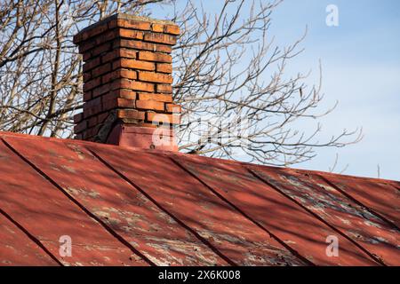 Dach und Schornstein eines alten Hauses - Ziegel- und Metallstruktur. Stockfoto