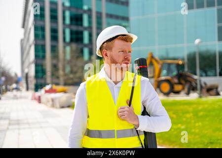 Architekt arbeitet mit sicherer Kleidung und hält ein Zugrohr neben der modernen Baustelle in der Stadt Stockfoto