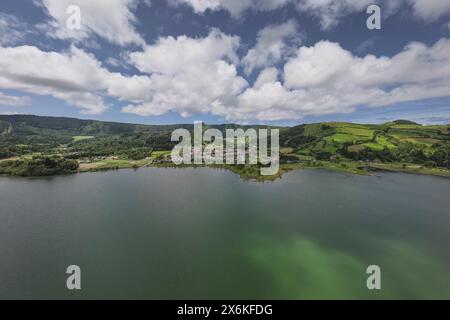 Aus der Vogelperspektive auf die kleine Stadt Sete Cidades am Kratersee Lagoa Azul auf der Insel Sao Miguel, Azoren. Stockfoto