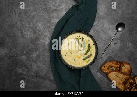 Eine Schüssel mit samtiger weißer Spargelsuppe, elegant garniert mit leuchtend grünen Spargelsprossen Stockfoto