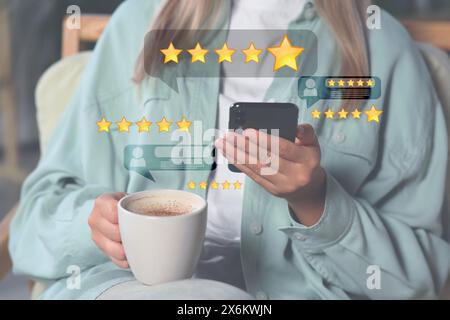 Frau verlässt Service-Feedback mit Smartphone, während sie Kaffee trinkt, Nahaufnahme. Bewertungen und Sterne in der Nähe des Geräts Stockfoto