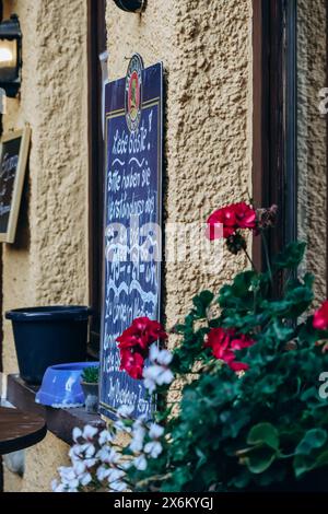 Füssen, Deutschland - 14. August 2023: Fenster mit Blumen und Restaurantmenü auf Tafel Stockfoto