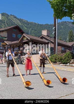 Während des Maifestes in Leavenworth, Washington, spielen Menschen in traditioneller deutscher Kleidung große Alphörner. Stockfoto
