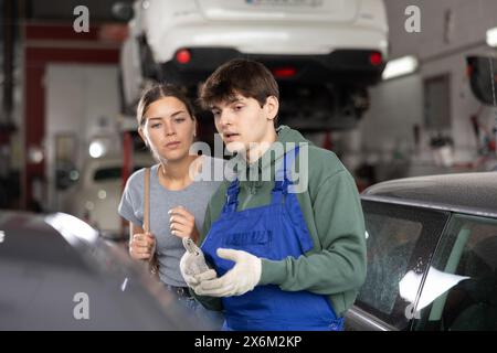 Interessierte Kundin, die Autoreparaturen mit einem Mechaniker bespricht Stockfoto