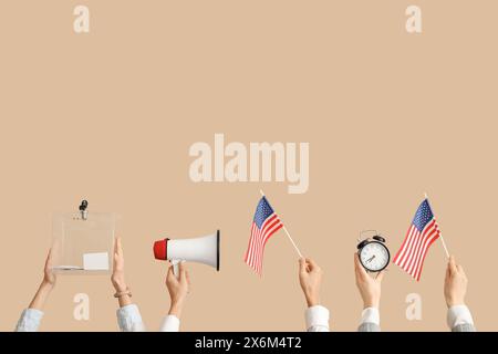 Zeiger mit Stimmzettel, USA-Flaggen, Megaphon und Wecker auf beigefarbenem Hintergrund. Wahlkonzept Stockfoto