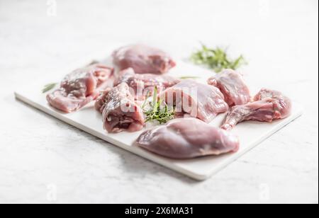 Portioniertes rohes Kaninchen mit Rosmarin auf einem Schneidebrett Stockfoto