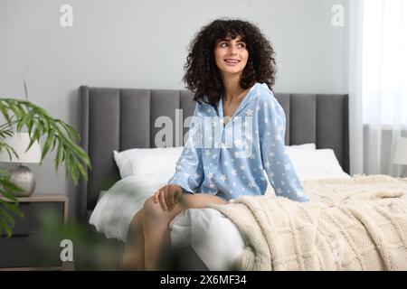 Schöne junge Frau im stilvollen Pyjama auf dem Bett zu Hause Stockfoto
