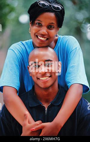 Ein schwarzer Mann und eine schwarze Frau posieren für ein Bild und lächeln in die Kamera. Sie stehen eng zusammen, sehen selbstbewusst und glücklich aus. Stockfoto