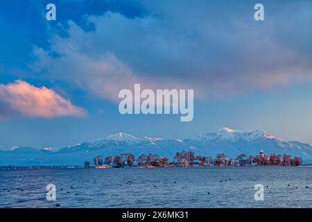 Chiemsee und schneebedeckte Fraueninsel mit Chiemgauer Alpen im Hintergrund, Chiemsee, Chiemgauer Alpen, Oberbayern, Bayern, Deutschland Stockfoto