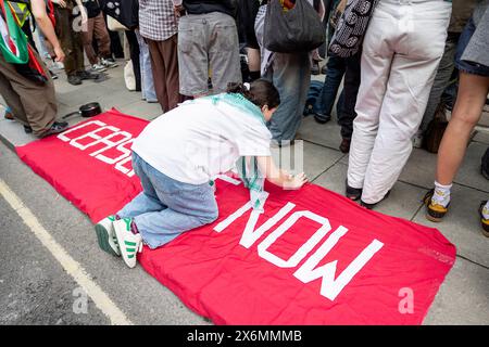 Ein Student wird gesehen, wie er ein Banner auf dem Boden vor dem Holborn Campus der UAL fixiert. Studenten der UAL (University of the Arts London) werden auf ihrem Universitätscampus gesehen, während sie mit dem Vizekanzler eine Diskussion über den Stand der Universität zum Israel-Gaza-Krieg halten. Später zog der Student auf den Central St Martin Campus und begann sein Lager, bis die Universität ihren Bedarf erfüllt. Studenten renommierter Universitäten in ganz Großbritannien schließen sich der neuen Welle der Besetzung und des Campings auf ihrem Universitätscampus seit Ende April an, inspiriert von den Studenten aus den USA, um diese zu drängen Stockfoto